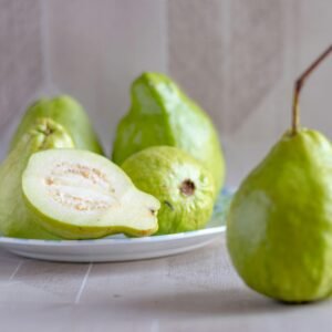 Fresh green guavas on a plate, showcasing their vibrant color and texture.