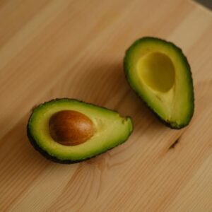A pair of fresh avocado halves showcasing vibrant green flesh on a wooden table.