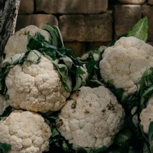 A close-up of fresh and raw organic cauliflowers with leaves, perfect for healthy cooking.