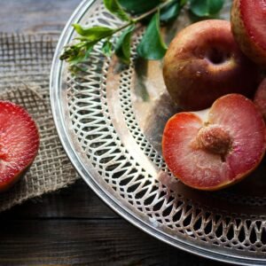 Juicy ripe red plums on a decorative silver plate, capturing freshness and health benefits.